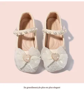 Macro detail of girls' white Mary Jane shoes with glitter toe and mesh bow decoration