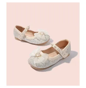 Close-up of girls silver sequin princess shoes with organza bow and pearl details