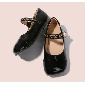 Detail von schwarzen Lack-Mary-Janes mit Goldketten, Perlen und Strallschnallen