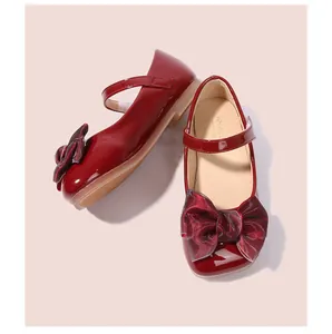 Détail de chaussures Mary Jane en cuir verni rouge avec nœud pailleté et semelle souple