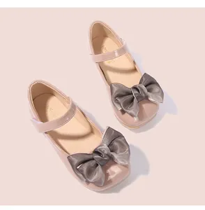 Détail de chaussures filles en cuir verni rose avec grand nœud en organza gris