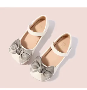 Gros plan de chaussures Mary Jane blanches pour filles avec un grand nœud en tulle gris