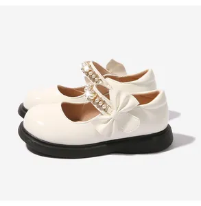 Detalle de zapatos Mary Jane beige para niña con lazo y perlas sobre suela negra gruesa