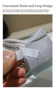 Detail of silver glitter girl shoes featuring velcro strap and heart charm on soft leather