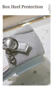 Macro shot of silver sequin heel with heart-shaped rhinestone pendant and buckled strap