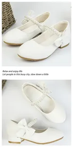 Close-up of white Mary Jane girl's shoes with pearl strap and bow detail on low block heel