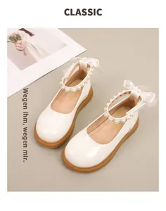 Detail van witte meisjes Mary Jane schoenen met parelbandje en satijnen strik op beige