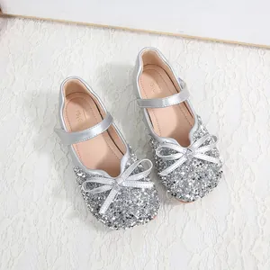 Detail von silbernen Mädchen-Mary-Janes mit Glitzerschleifen und Spiegel-Finish