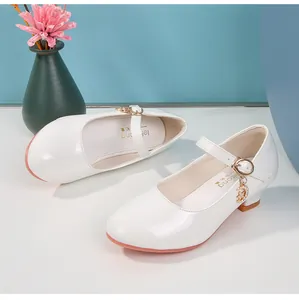 Dettaglio di scarpe Mary Jane in pelle verniciata bianca con ciondolo luna gioiello