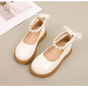 Detail van witte Mary Jane schoenen voor meisjes met parelbandjes en zijden strikjes