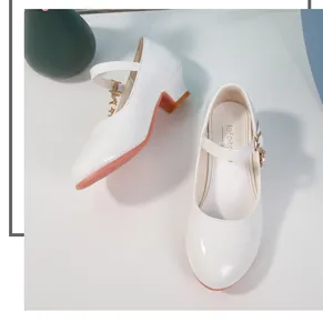 Dettaglio di scarpe Mary Jane bianche lucide con ciondolo a stella dorata