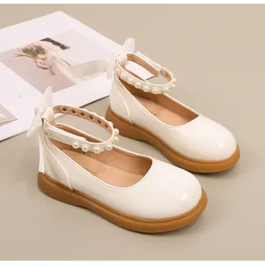 Detail van crème Mary Jane schoenen met parelbandje en een grote satijnen strik