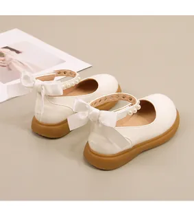 Detail van witte Mary Jane schoenen met parelbandje, satijnen strik en rubberen zool