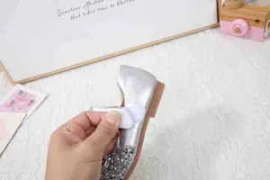Detail eines silbernen Pailletten-Prinzessinenschuhs mit verstellbarem Klettverschluss