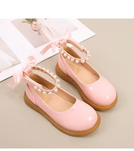 Detail van roze lakleren Mary Jane schoenen met parelbandje en grote satijnen strik