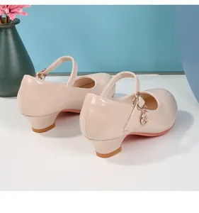Dettaglio di scarpe Mary Jane beige in vernice per bambine con ciondolo a luna d'oro