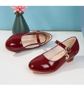 Dettaglio di scarpe Mary Jane in vernice bordeaux con ciondoli a stella e luna lucenti