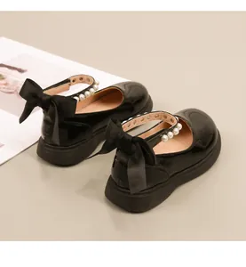 Detail van zwarte lakschoenen voor meisjes met een parelgesp en een zijden strikaccent