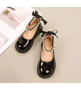 Detail van zwarte lakleer Mary Jane schoenen voor meisjes met parelbandje en satijnen strik