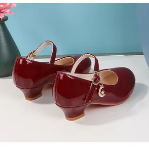 Dettaglio di scarpe Mary Jane in vernice bordeaux con ciondoli stella luna e tacco largo