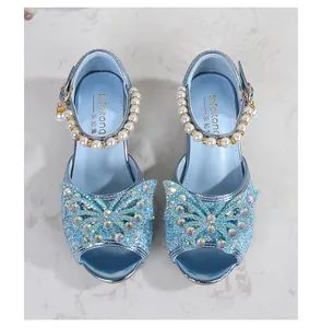 Detail of light blue glitter sandals featuring a large rhinestone bow and pearl charms