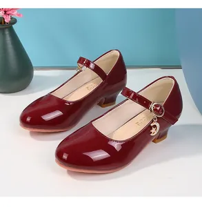 Dettaglio di scarpe Mary Jane in vernice bordeaux con ciondoli a stella e luna