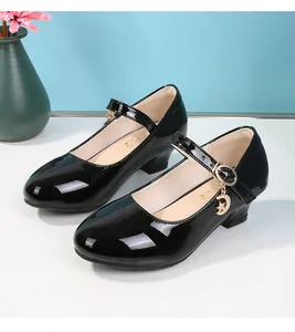 Dettaglio di scarpe Mary Jane in vernice nera con pendenti dorati a luna e stelle