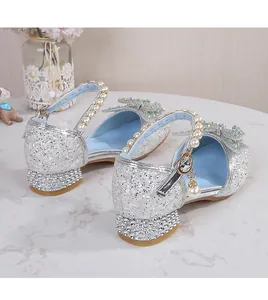 Detail of girls' silver sequin shoes with pearl ankle straps and rhinestone bow
