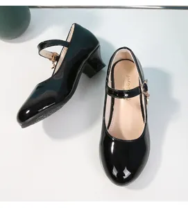 Dettaglio delle scarpe Mary Jane in vernice nera con fibbia dorata e tacco largo per bimbe
