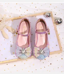 Detail view of pink glitter girls' heels with a large sequin bow and crown charm decoration