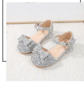 Macro shot of silver sequined girls princess shoes with bow and transparent low heel