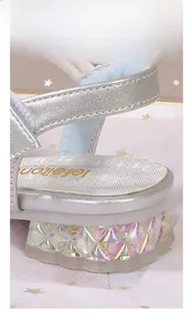 Détail d'une sandale de princesse argentée avec talon en cristal transparent pour fille