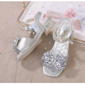 Détail de sandales argentées pour filles avec fleur en cristal, brides perles et talons pailletés