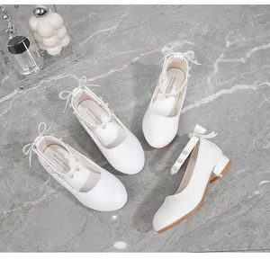 Close-up of white Mary Jane shoes with pearl ankle strap and ribbon bow detail