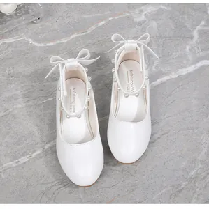 Close-up of white girls' princess shoes featuring pearl ankle straps and a bow detail