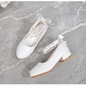 Close-up of girls white Mary Jane shoes with elegant pearls and bow details