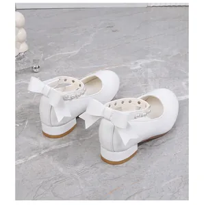 Detail of white Mary Jane shoes featuring pearl ankle straps and large back bows