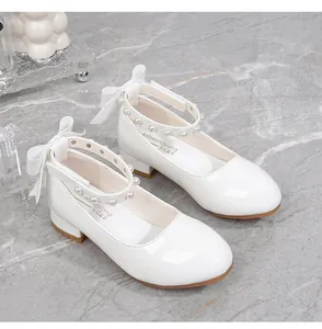 Close-up of white girls' Mary Jane shoes with pearl beads and silk ribbon bow detail