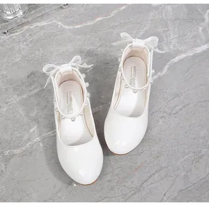 Detail of white patent leather girl shoes with pearl ankle strap and ribbon bow decoration