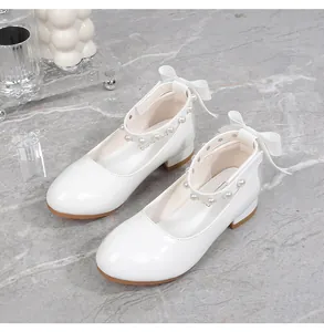 Close-up of white patent leather girls shoes with pearl strap and bow detail