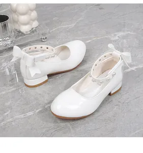 Detailed view of white Mary Jane shoes with pearl straps and silk bow accents