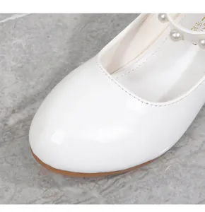 Close-up of white patent leather girls Mary Jane shoes with elegant pearl strap detailing