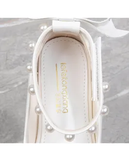 Detailed top view of white girl's princess shoes with pearls and bow decoration