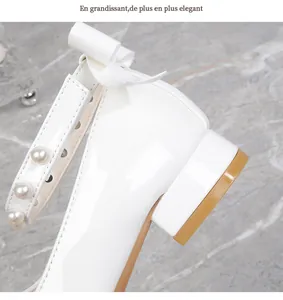 Detailed close-up of girls' white patent leather shoes with pearls and heel bow detail