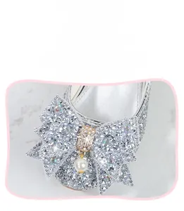 Détail de chaussures argentées pour filles avec nœud en strass et pendentif perle