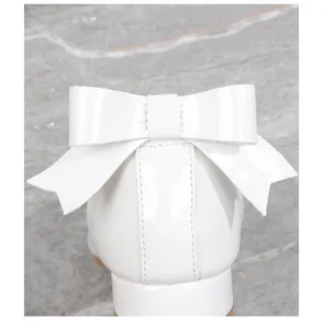 Close-up of girls white patent leather princess shoes with elegant back bow detail