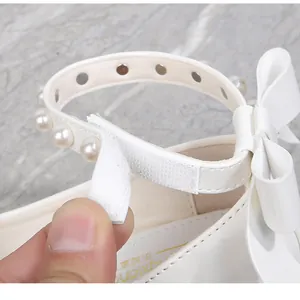 Detail of girls white leather princess shoes with pearl straps and velcro closure