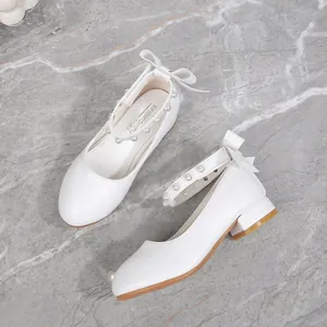 White girls Mary Jane dress shoes with pearl straps and bow details on marble background