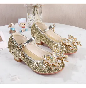 Détail de chaussures dorées pailletées pour enfants avec nœud et pendentif en perle