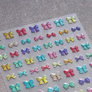 Colorful 3D bow nail art stickers with glitter laser finish on grey textured surface